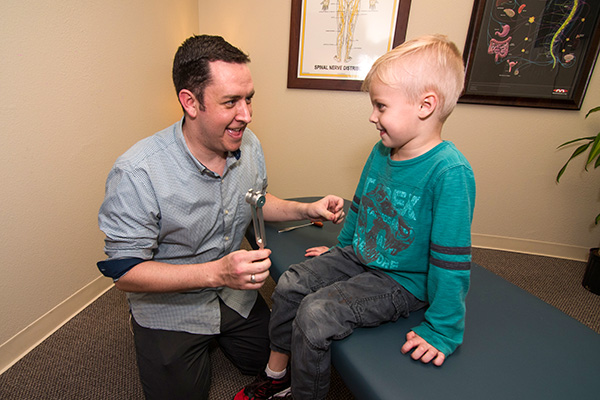 A young child smiling at Dr. Kaleb Valdez during a chiropractic adjustment appointment